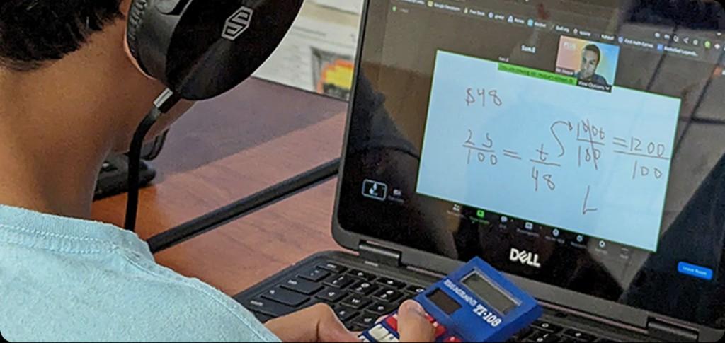 Student wearing headphones at a laptop during a live online tutoring session with a tutor on video