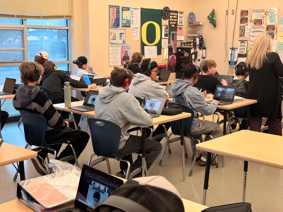 Students in a classroom with laptops and headphones